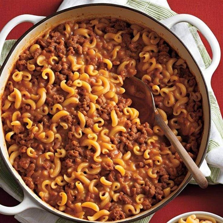 a pot filled with macaroni and cheese on top of a red table cloth