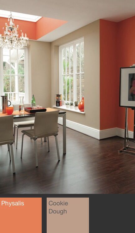 an orange and beige dining room with wood floors, chandelier, windows, and table