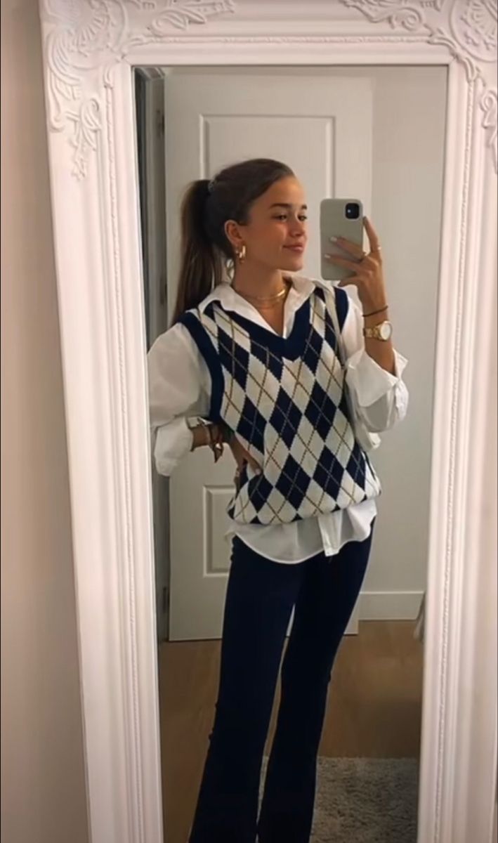 a woman taking a selfie in front of a mirror wearing a sweater and jeans