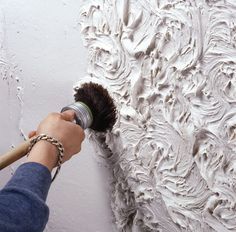 a person painting a wall with white paint