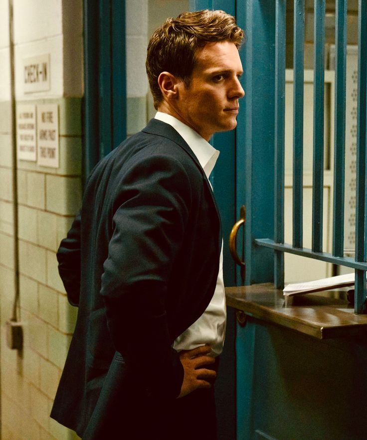 a man in a suit standing next to a jail cell