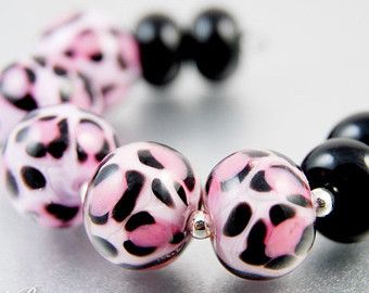 two black and pink beads with white spots on them are sitting next to each other