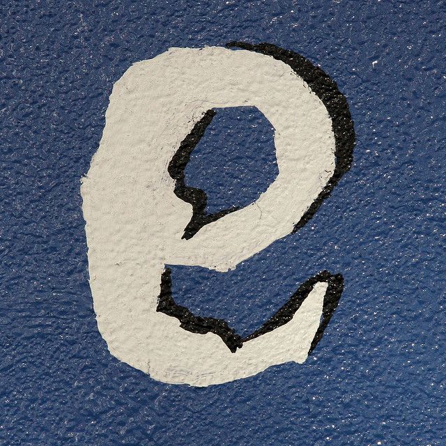 the letter q is painted with black and white paint on a blue background, which has been stenciled