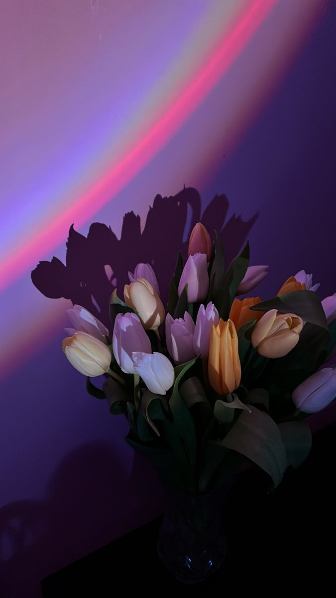 a vase filled with lots of flowers on top of a table next to a wall