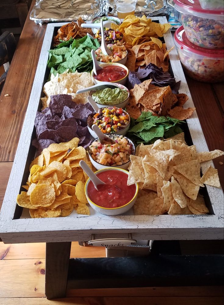 a tray with chips, salsa and guacamole on it next to other foods