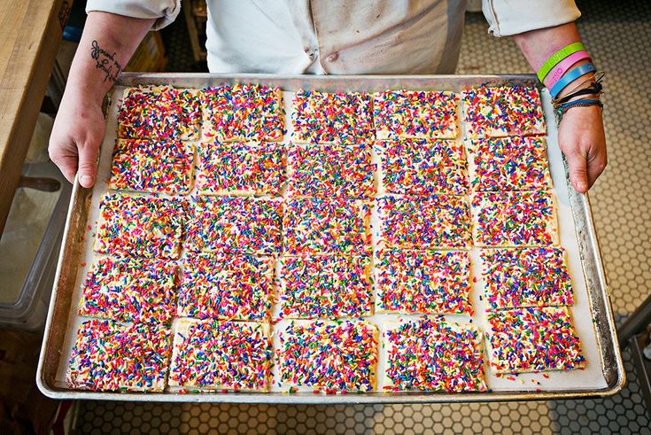 a person holding a tray full of sprinkles on top of a table