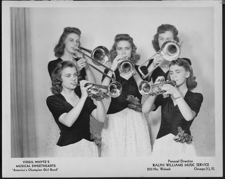 an old black and white photo of four women with musical instruments in their hands, posing for the camera