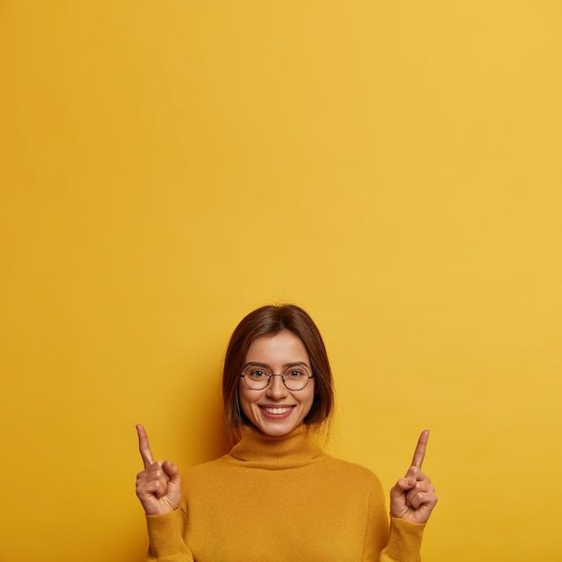 a woman with glasses is holding two fingers up in the air and smiling at the camera