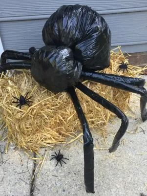 a large black spider sitting on top of hay next to a door with its legs wrapped in plastic