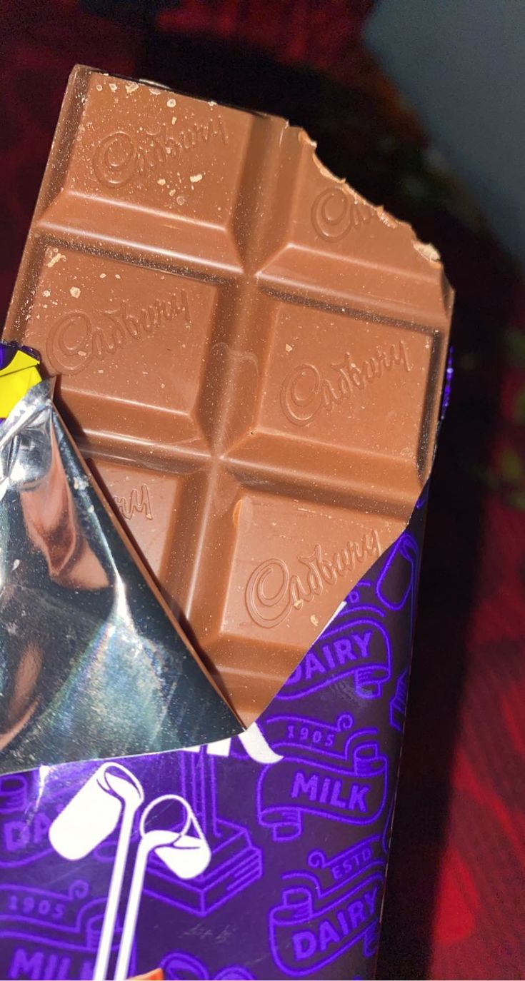 a bar of chocolate sitting on top of a purple and white wrapper next to it