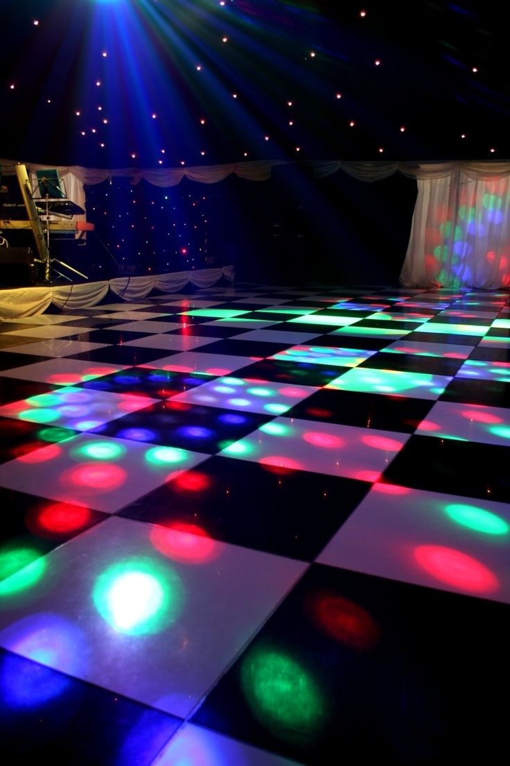 a dance floor with colorful lights on it and a piano in the background at night