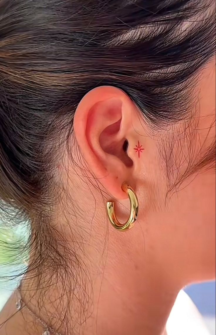 a close up of a person's ear with a small star tattoo on it