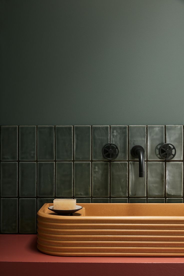 a bathroom sink with soap dispensers on the wall and tiled back splash