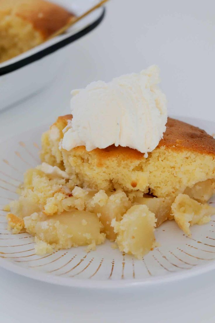 a piece of cake sitting on top of a white plate next to a bowl filled with whipped cream