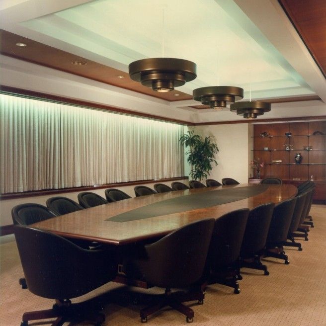 an empty conference room with chairs and a large table in front of a wall - mounted screen