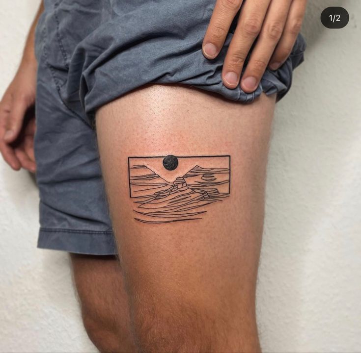 a man with a small tattoo on his thigh that has mountains and waves in the background