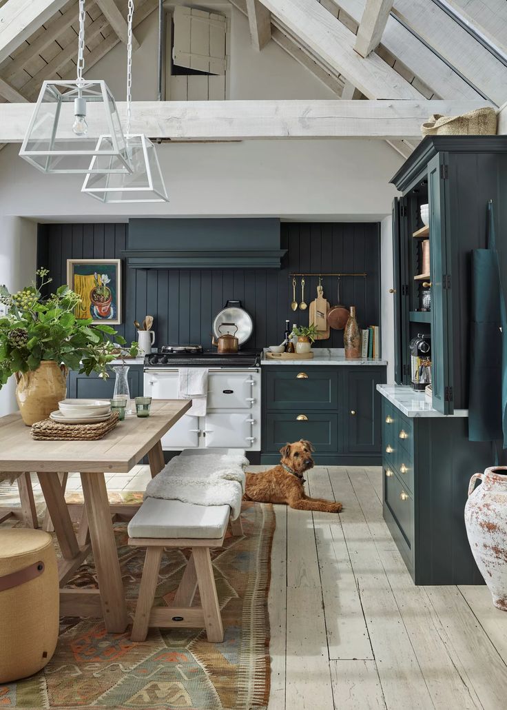 a dog is sitting in the middle of a kitchen with dark green cabinets and white appliances