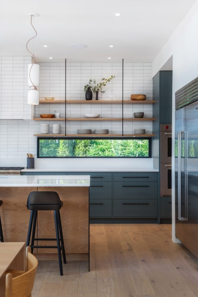 a kitchen with wooden floors and white tile on the walls, along with black bar stools