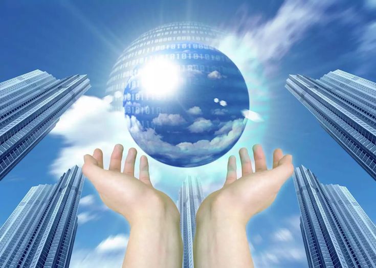 two hands holding up a crystal ball in front of some tall buildings and blue sky