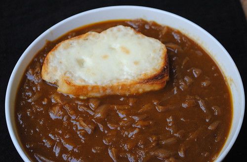 a bowl filled with beans and bread on top of a black tableclothed surface