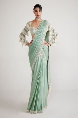 Powder mint green pre-draped saree with pearls and mirror embroidered scalloped border. Comes with chandelier drop hand embroidered, padded blouse.
Components: 2
Pattern: Hand Embroidered
Type Of Work: Chandelier Pearl Drop
Neckline: Sweetheart
Sleeve Type: Full
Fabric: Blouse - Georgette, Saree - Satin Chiffon
Color: Green
Other Details: 
Attached lining
Tassel drops
Back cutout blouse
Scalloped hem
Blouse length: 13.5 inches
Model height: 5ft 6inches, wearing size 32
Occasion: Reception,Cockta Ready Saree, Cinderella Fashion, Pre Draped Saree, Ready Made Saree, Saree Satin, Bhumika Sharma, Skirt Saree, Green Chandelier, Green Chandeliers