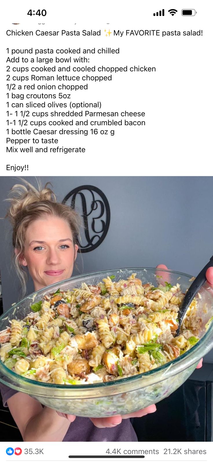 a woman holding a large glass bowl filled with pasta and other food on top of a table