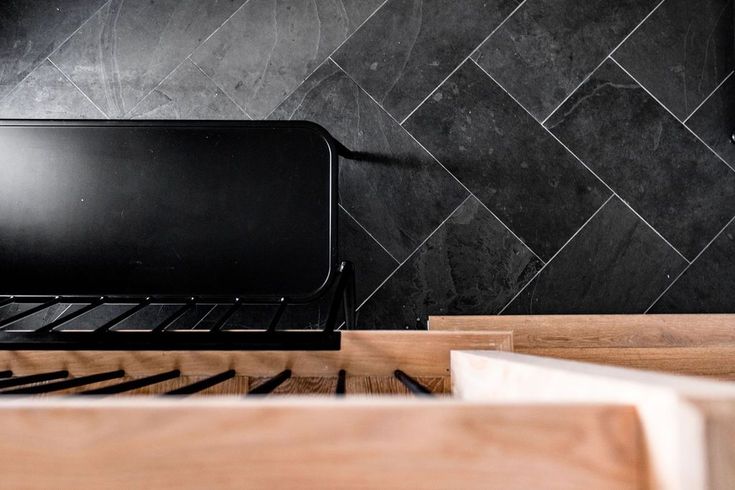 a stove top oven sitting inside of a kitchen next to a wooden shelf and tiled wall