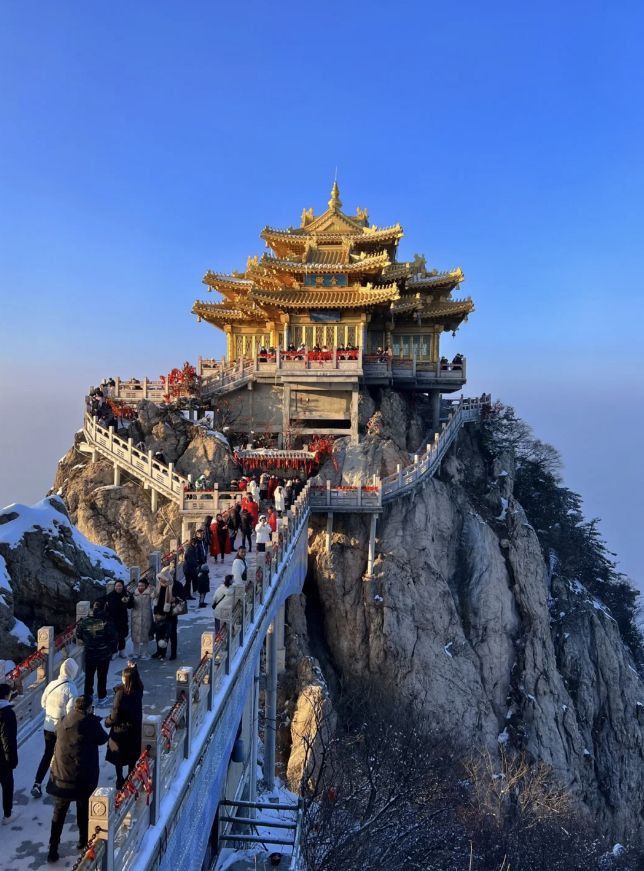 people are walking up and down the stairs on top of a mountain with a pagoda in the background