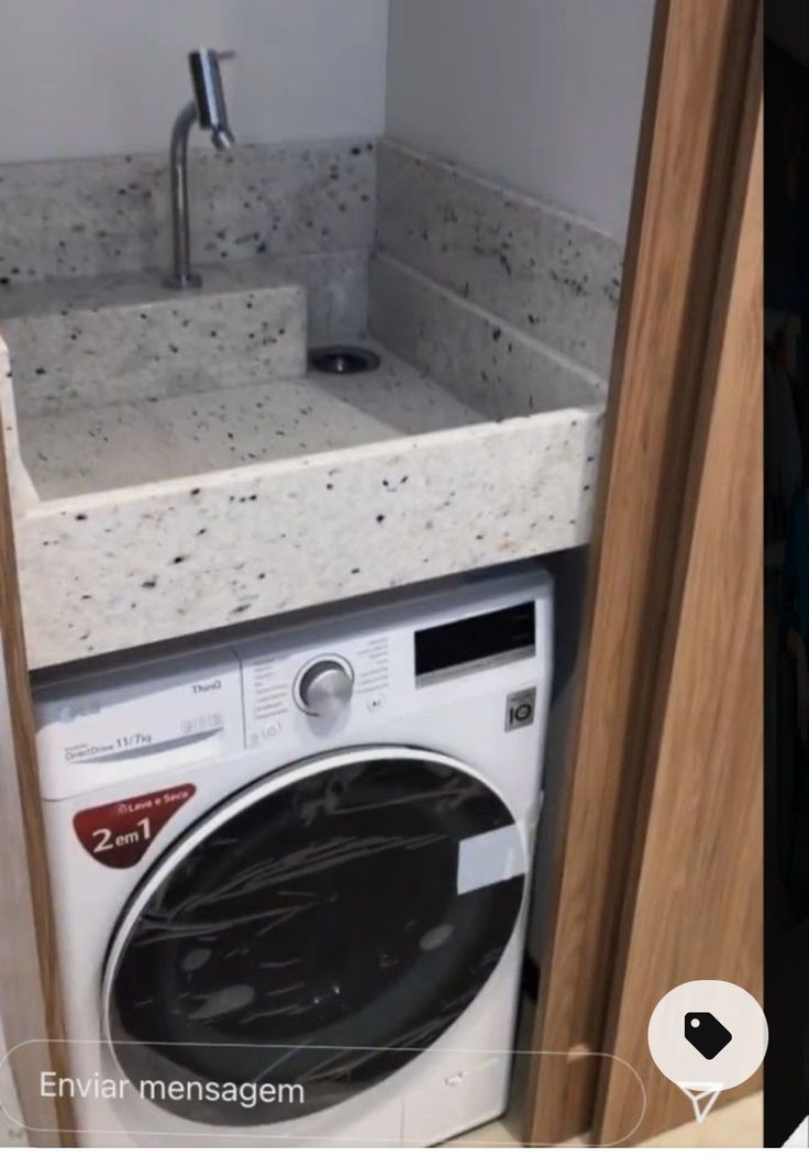 a white washer sitting next to a sink in a bathroom under a faucet