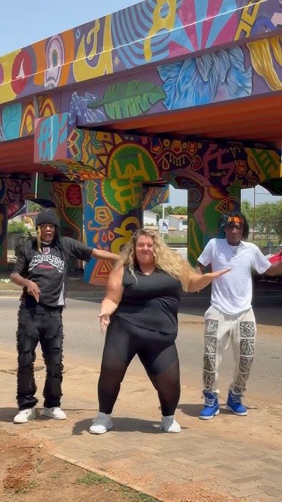 a group of people standing around each other in front of a colorful structure with graffiti on it