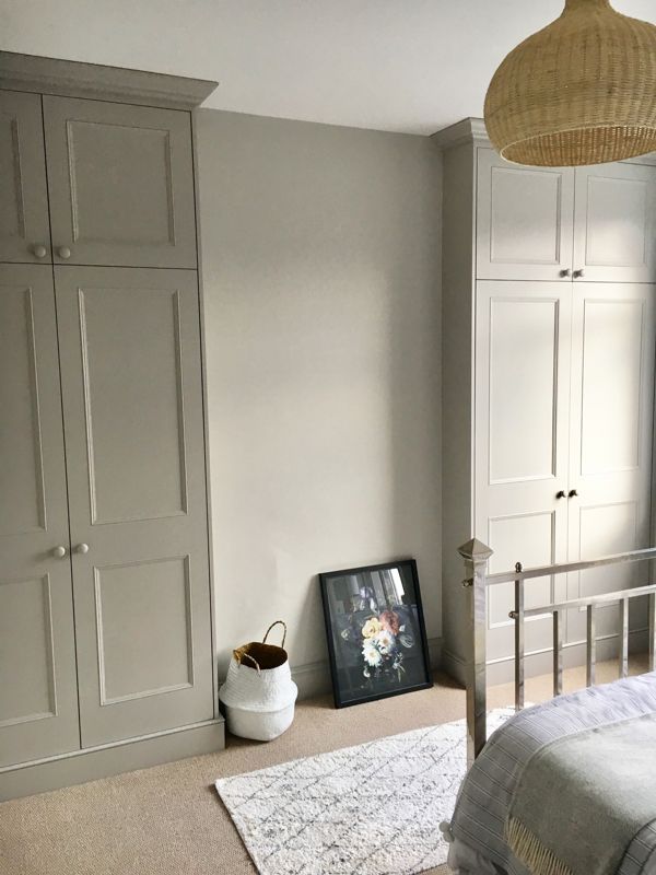 a bed room with a neatly made bed and white cupboards