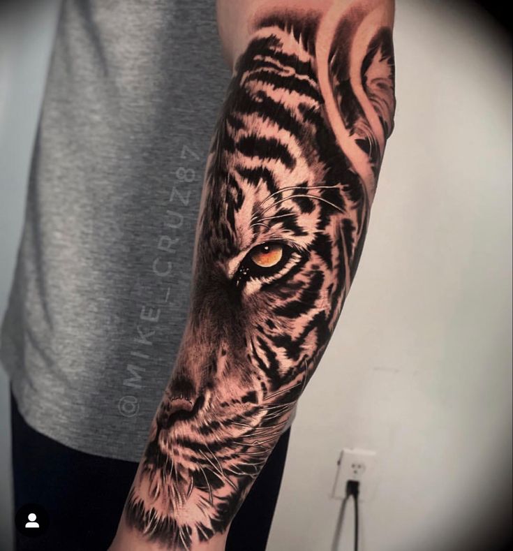 a man's arm with a tiger tattoo on it and an orange eye in the center