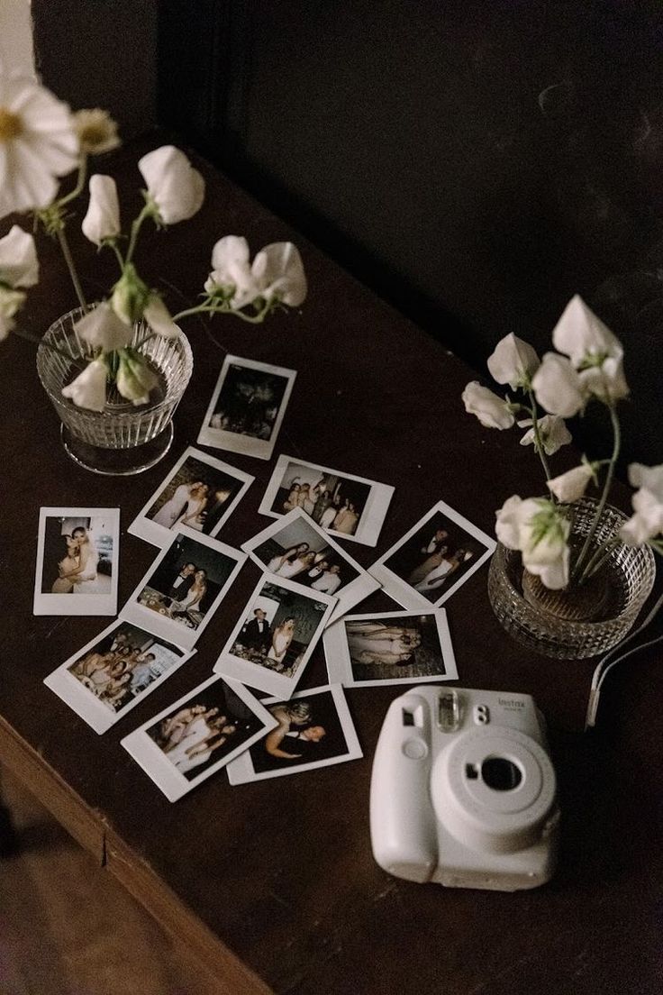 several polaroid pictures are placed on a table next to flowers and an old camera