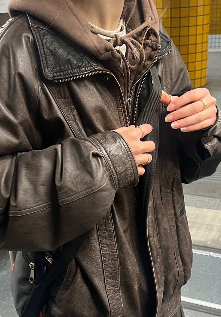 a woman in a leather jacket is holding onto her purse