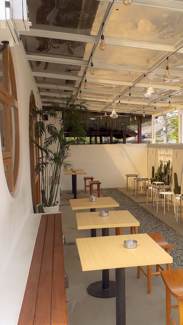 tables and chairs are lined up in the room with plants on the wall behind them