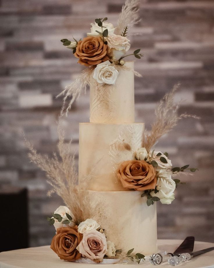 a three tiered wedding cake with flowers and feathers