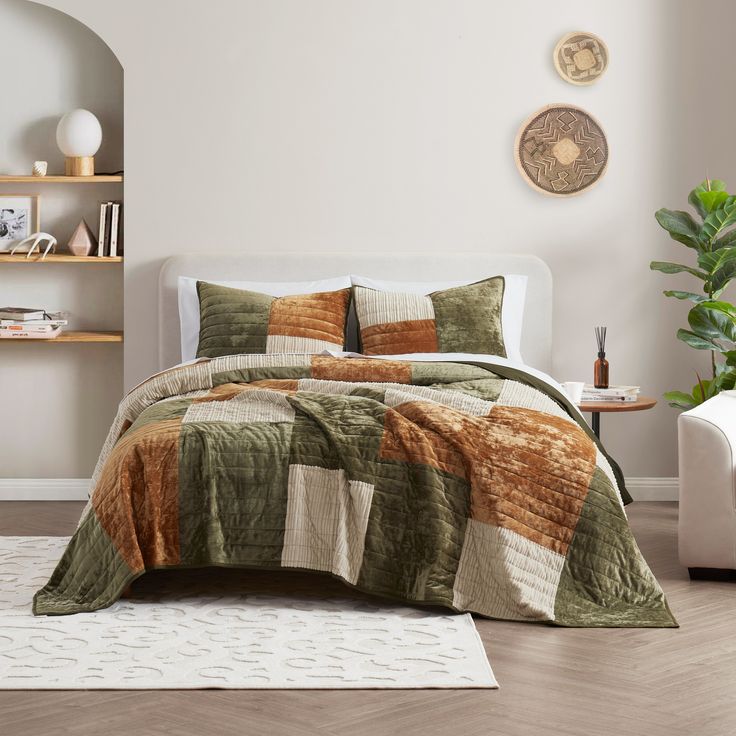 a bed in a bedroom with a green and brown quilt