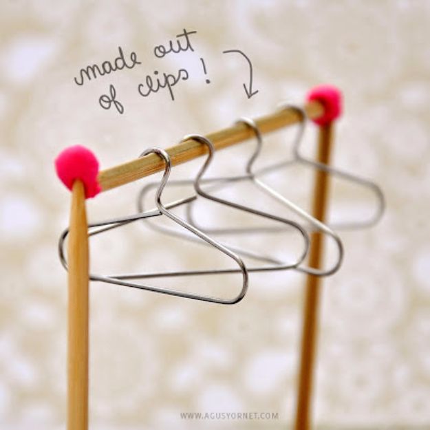 three wooden clothes pins with pink balls on them are standing next to each other in front of a white wall