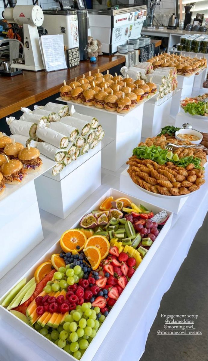 many different types of food are on display in white trays at a buffet table