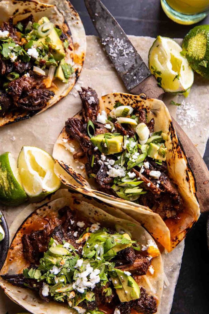 three tacos with shredded meat, avocado and cilantro on top