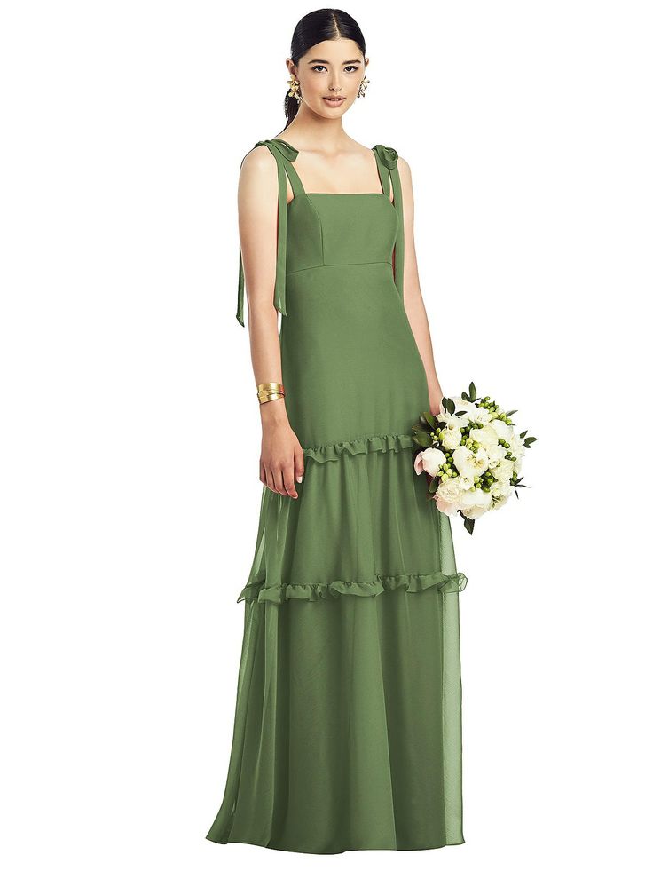 a woman in a long green dress holding a bouquet and wearing a white flower arrangement