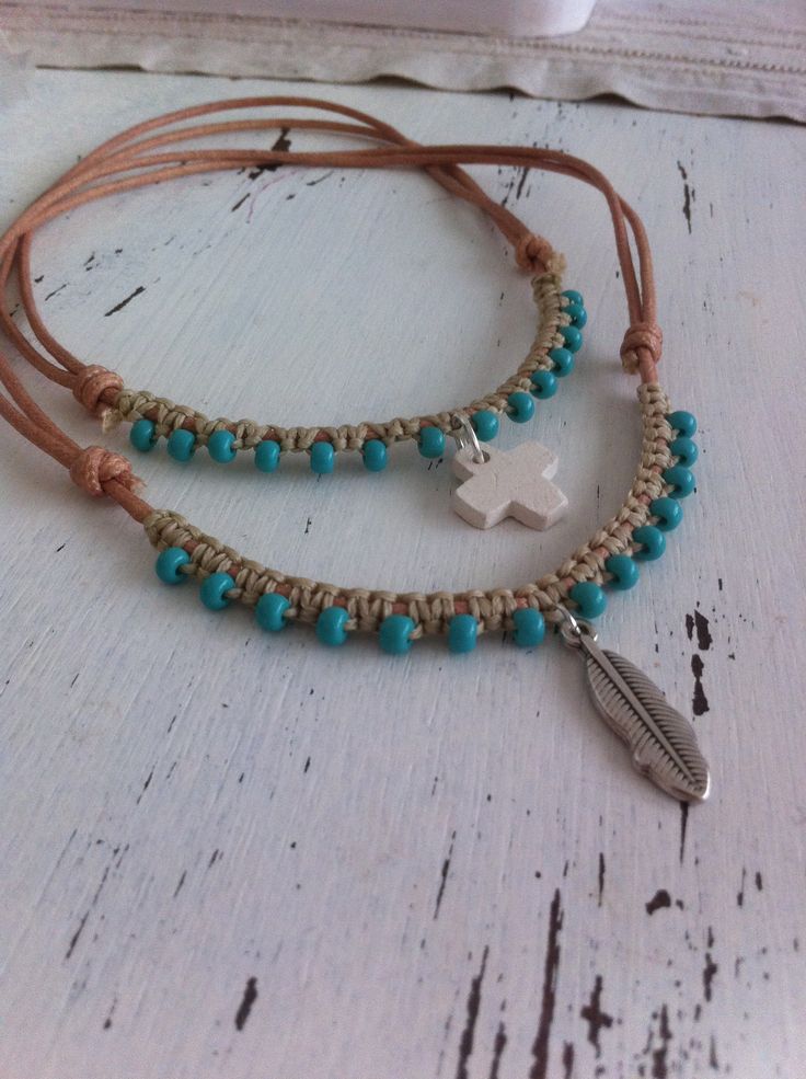 two bracelets with beads and a cross on them sitting on top of a table