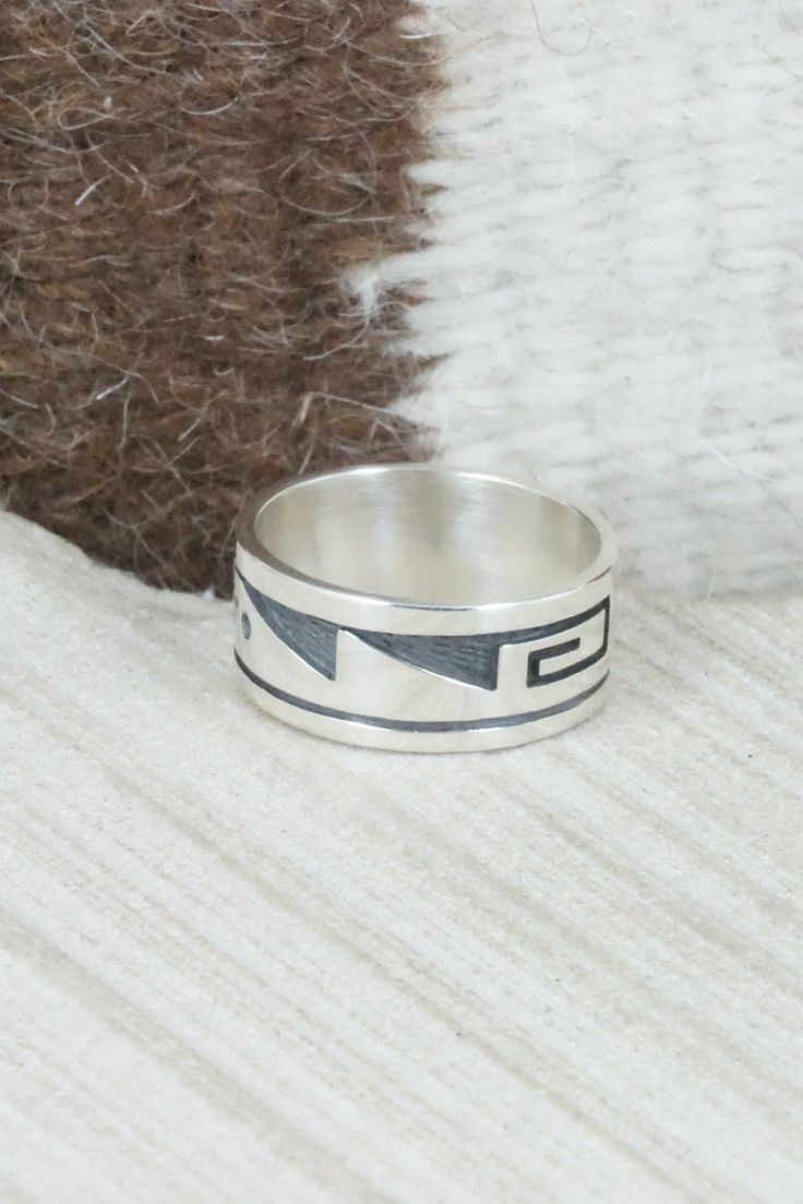 This sterling silver ring was made by Hopi silversmith Timothy Mowa. The inside is stamped sterling.Size: 10Length: 7/8"Width: 3/8"Free shipping on all orders! We ship with USPS and always include tracking. All orders ship within a day of payment.Returns are accepted up to 30 days after you receive your order. Just send us a message. Our shop offers cash back or store credit. The item must be returned in new condition. Artisan Engraved Sterling Silver Ring 925, Stamped Sterling Silver Wide Band Jewelry, Artisan Sterling Silver Ring With Etched Details, Artisan Sterling Silver Etched Rings, Collectible Sterling Silver Ring With Wide Band, Sterling Silver Stamped Rings For Collectors, Artisan Sterling Silver Wide Band Ring, Sterling Silver Inlay Ring, Native American Jewelry