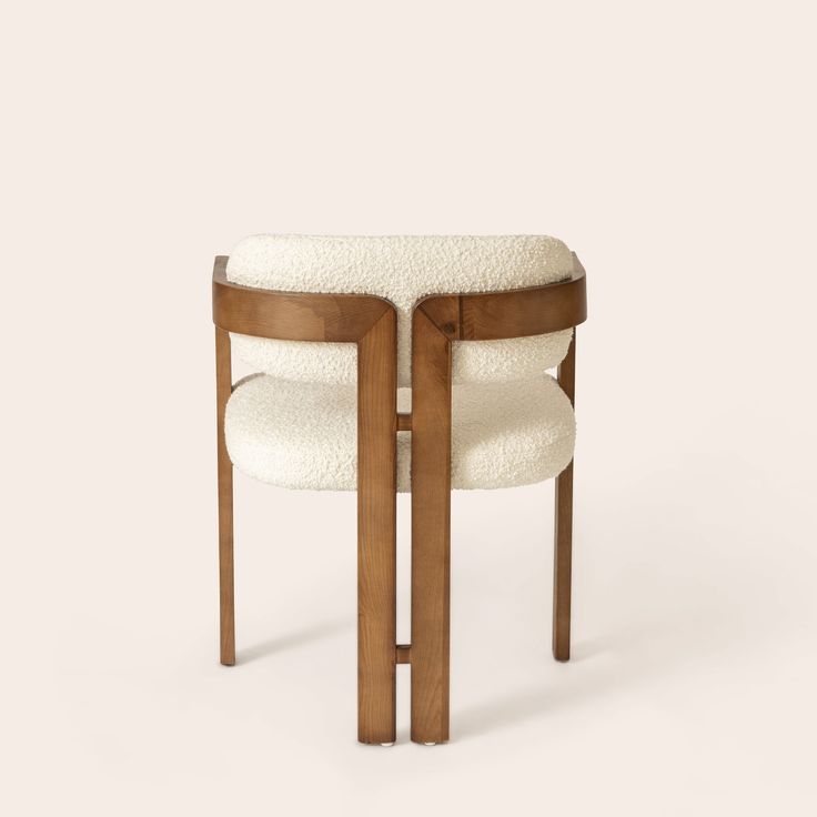 a white chair with wooden legs and a round seat cushion on the back of it