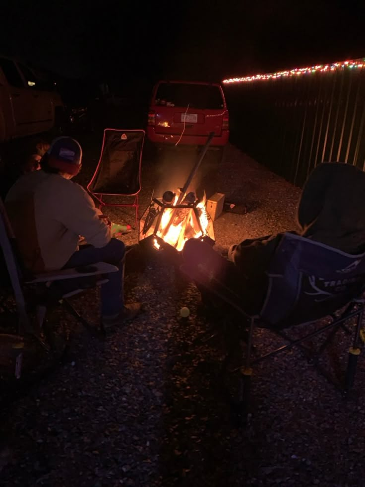 two people sitting around a campfire at night