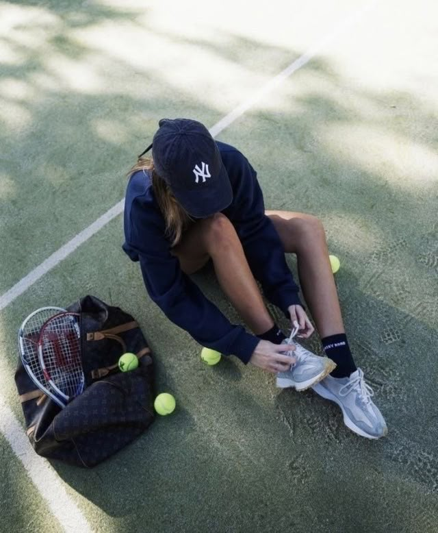 a woman sitting on the ground with tennis balls