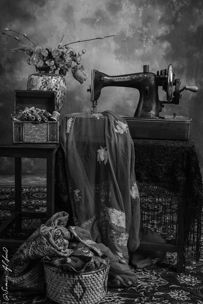 an old fashioned sewing machine sitting on top of a table next to a basket filled with flowers