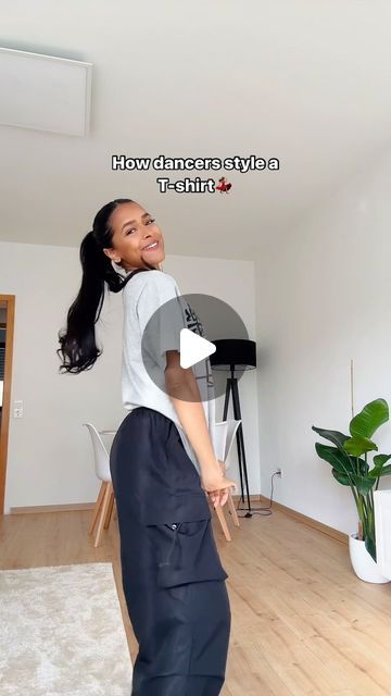 a woman standing on top of a hard wood floor next to a white wall in a living room