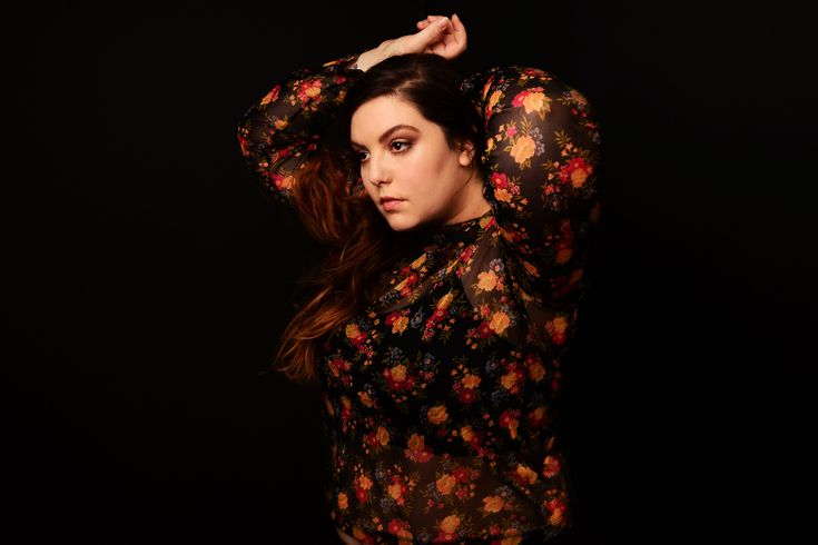 a woman is posing with her hands on her head