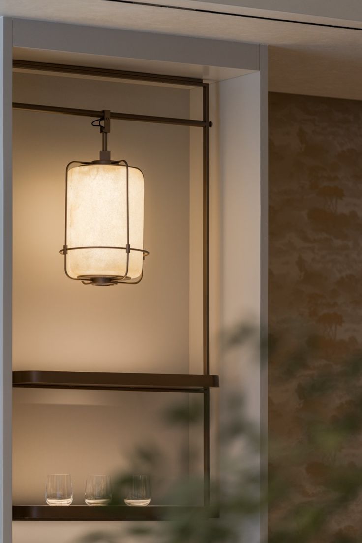 a light hanging from the side of a wall next to a shelf with wine glasses on it